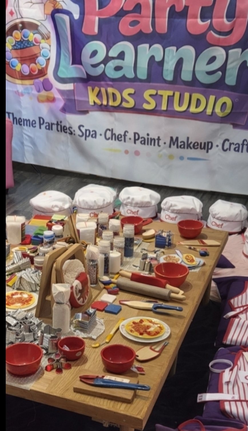 Chef Party — Decorating Experience long table with chef hats, decorating tools, kid-friendly accessories and Party Learners Kids Studio Theme Parties banner: Spa, Chef, Paint, Makeup, Craft