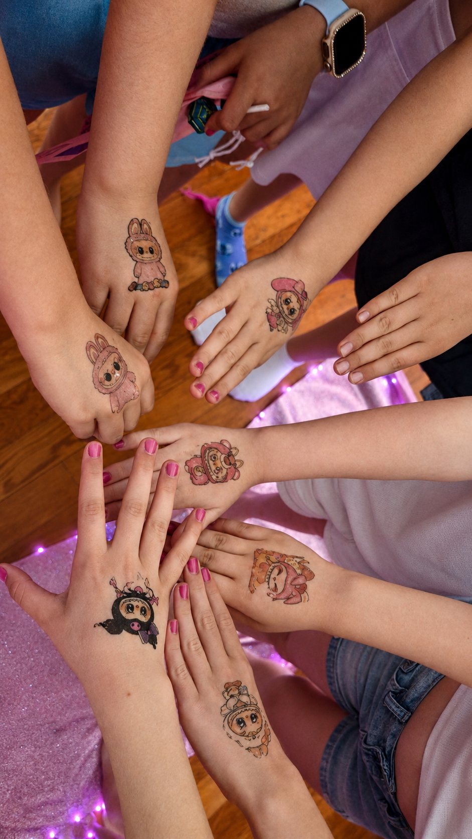 Close-up of kids' hands showing colorful glitter tattoos in a circle at a Divas Glam Spa Party