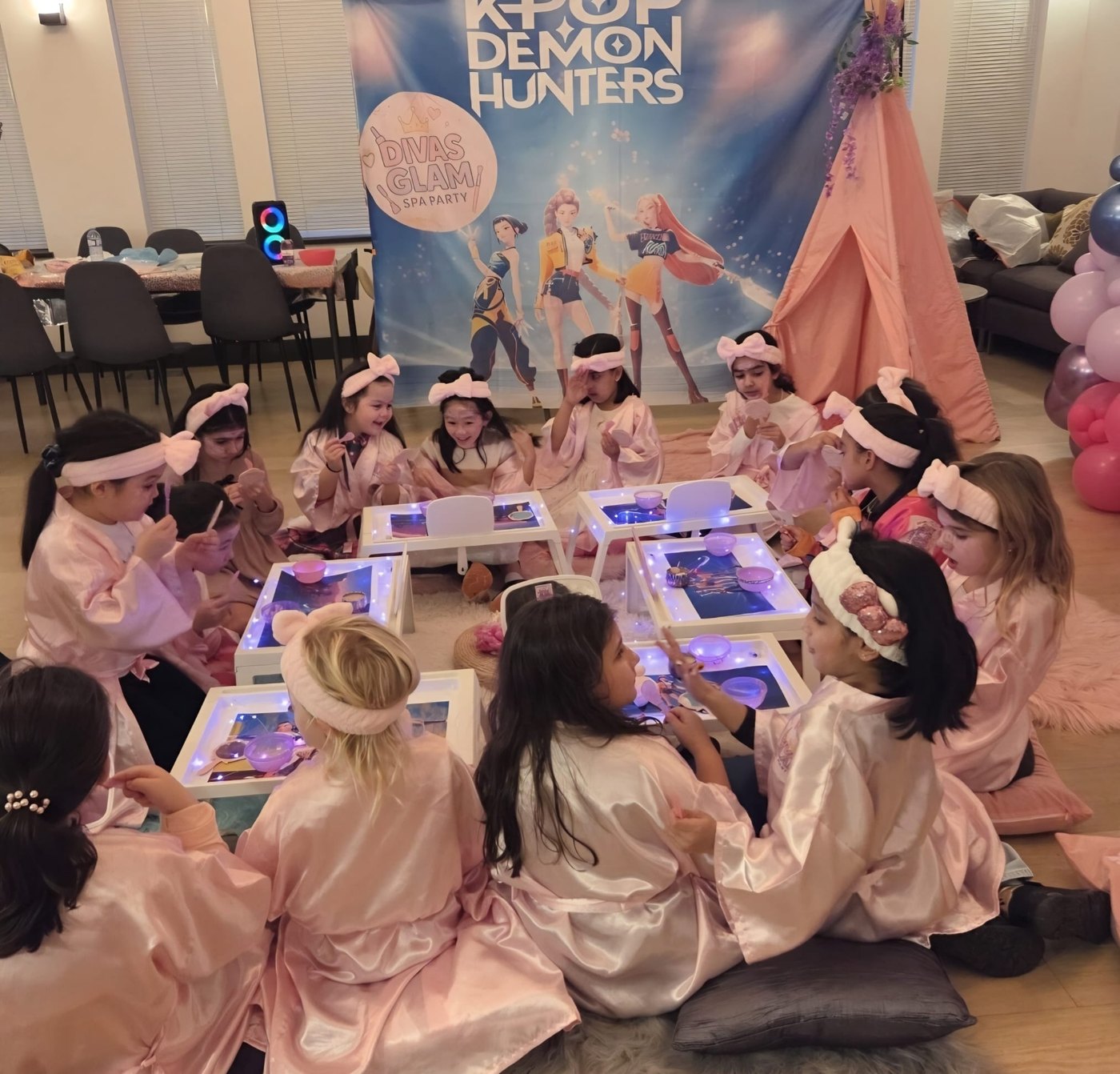 Real Divas Glam Spa Party — group of girls in pink robes around white spa trays at a themed party