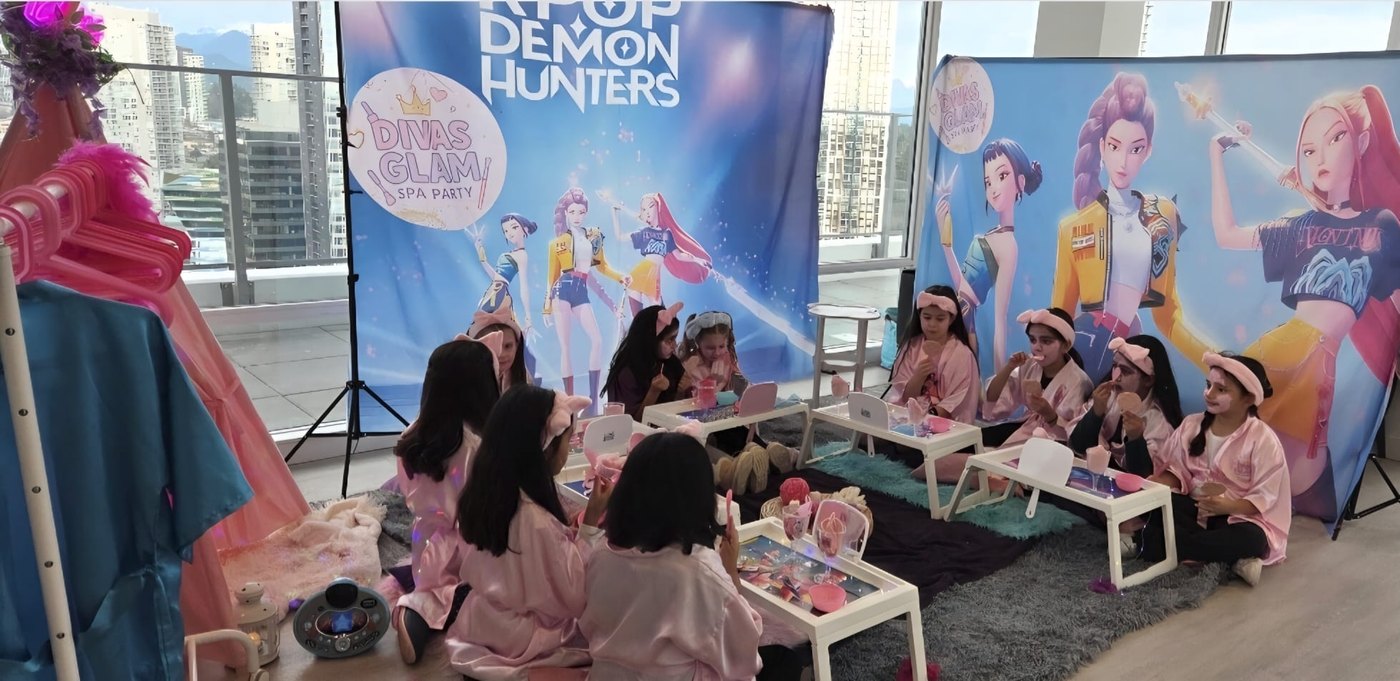 Wide group of girls in pink robes celebrating a Divas Glam Spa Party in front of a Vancouver skyline window