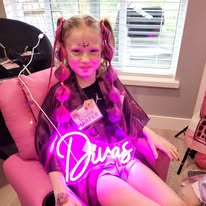 Birthday girl portrait with a glowing DIVAS neon sign at a Divas Glam Spa Party