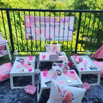 Outdoor Divas Glam Spa Party setup with white tables, pink décor and Divas Glam banner